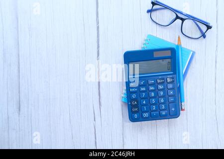 blue color calculator, notepad and pencil on wooden table  Stock Photo