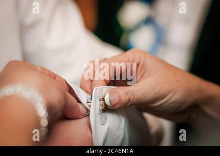 Woman fastens cufflink on the mans sleeve Stock Photo