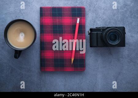 Classic camera with a red notepad and coffee on black background. Stock Photo