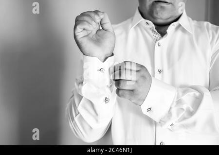 Groom in white shirt fastens button on sleeve Stock Photo