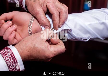 Man fastens cufflink on the grooms sleeve Stock Photo