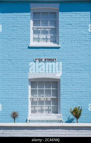 Exterior of old house with pastel blue wall and white window frames with High Street sign. Aldeburgh, Suffolk. UK Stock Photo