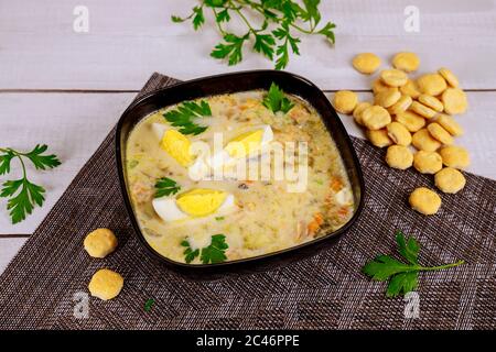 Creamy vegetable soup in black bowl with egg and crackers. Chinese cuisine. Stock Photo