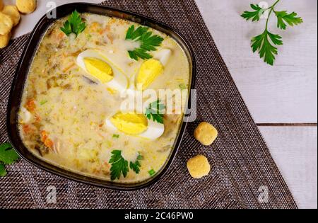 Creamy vegetable soup in black bowl with egg and crackers. Asian cuisine. Stock Photo