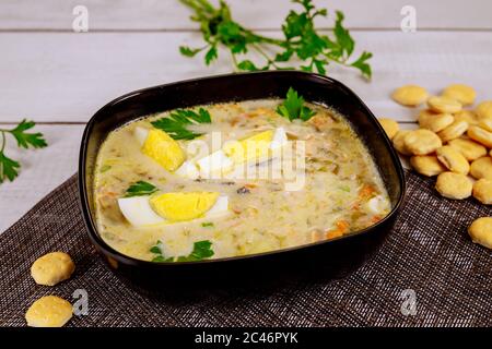 Creamy seafood soup in black bowl with egg and crackers. Chinese cuisine. Stock Photo