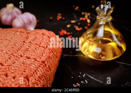 Uncooked ground beef with garlic and olive oil on black background. Close up. Stock Photo