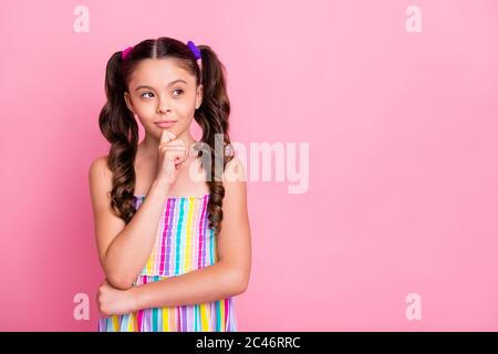 Photo of beautiful little lady two lovely cute curly tails good mood look interested side empty space tricky arm on chin wear colored summer dress Stock Photo