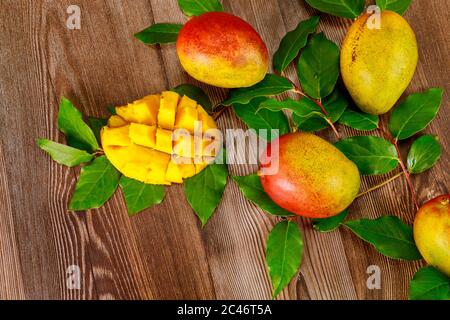 Ripe mango with green leaves on wooden background. Stock Photo