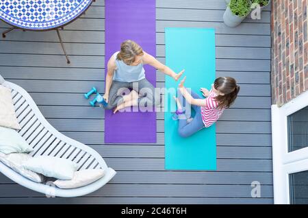 Overhead View Of Mother And Daughter Giving Each Other High Five After Exercising Together At Home On Deck Stock Photo