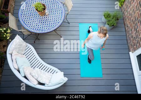 Overhead View Of Healthy Mature Woman At Home Exercising On Deck  With Dumbbell Hand Weights Stock Photo