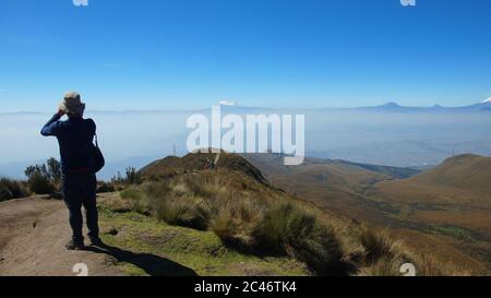 Quito, Pichincha / Ecuador - July 16 2017: Man on his back taking photos from the Rucu Pichincha to the city of Quito with the Antisana volcano in the Stock Photo