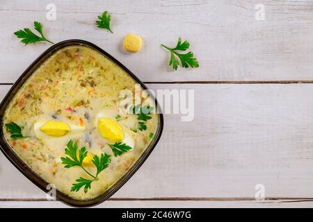Chicken and vegetable soup in black bowl with egg and crackers. Stock Photo