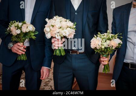 Mans in suits holding bouquet of flowers in the hands Stock Photo