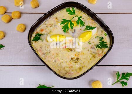 Creamy chicken soup in black bowl with egg and crackers. Stock Photo