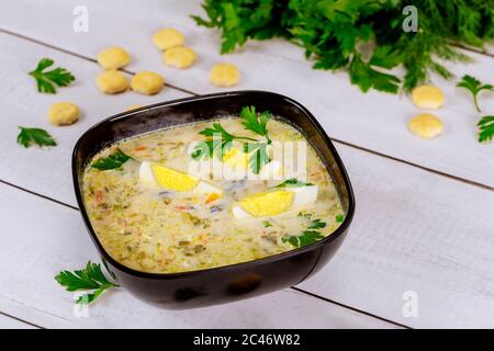 Healthy creamy vegetable soup in black bowl with egg and crackers. Stock Photo