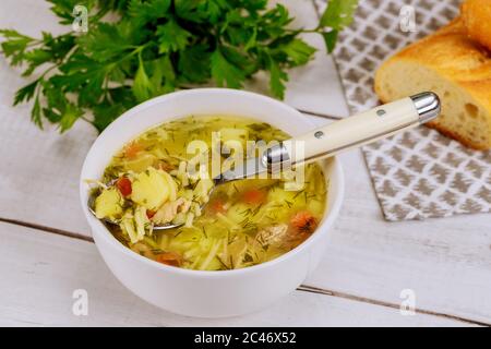 Hot homemade chicken noodle soup in spoon with parsley and bread. Stock Photo