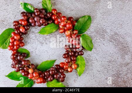 Pattern from red grapes and leaves on gray background. Stock Photo