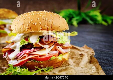 Honey ham sandwich with lettuce, tomato and cheese on dark background. Stock Photo