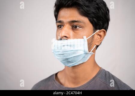 young man wearing medical mask below nose - concept showing of improper way of using face masks during coronavirus or covid-19 crisis. Stock Photo