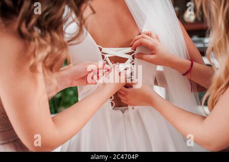 bridesmaids lace up the bride's dress Stock Photo