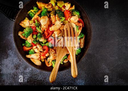 Delicious healthy stir fry vegetables with chicken in pan on dark surface. Stock Photo