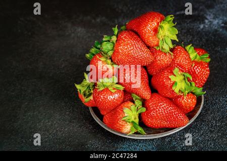 Juicy fresh strawberries in plate on dark background. Stock Photo