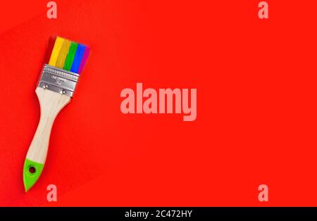 brush with rainbow color bristles on a red background. top view. space for text. Stock Photo