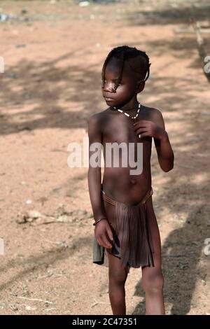 KAMANJAB, NAMIBIA - FEB 1, 2016: Little unidentified Himba girl in traditional dress shown in himba tribe village Stock Photo