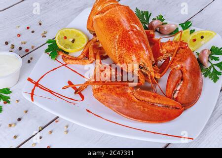 Cooked sea large lobster with lemon on white plate. Stock Photo