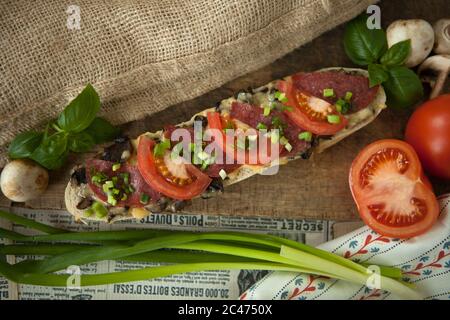 Italian bread, baguette with salami and yellow cheese wrapped in paper Stock Photo