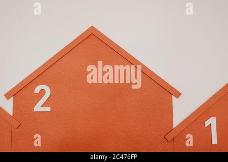 Close up shot of orange colored carton houses numbered on a grey background Stock Photo