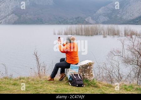 A tourist woman in hat and coat with a compass in nature Stock Photo