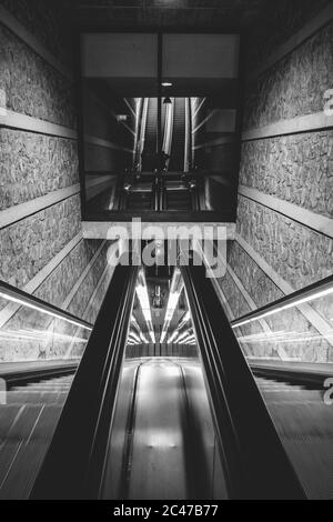Vertical grayscale shot of an escalator inside a building Stock Photo