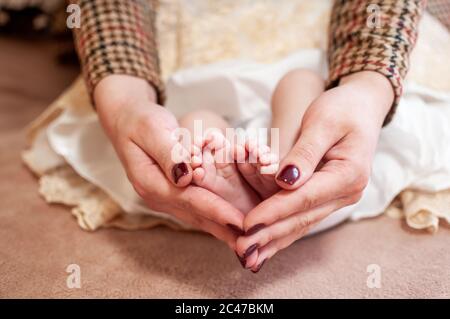 Pair of hans holding legs of newborn baby Stock Photo