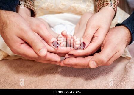 Pair of hans holding legs of newborn baby Stock Photo