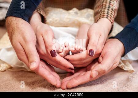 Pair of hans holding legs of newborn baby Stock Photo