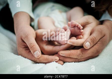 Pair of hans holding legs of newborn baby Stock Photo