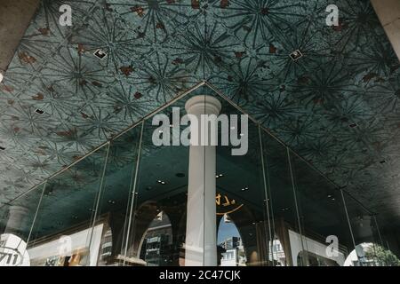 Ceiling of a building with green patterned tiles and a room made of  glass walls Stock Photo