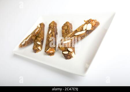Selective focus shot of an almond brittle bars placed in a white plate with white background Stock Photo