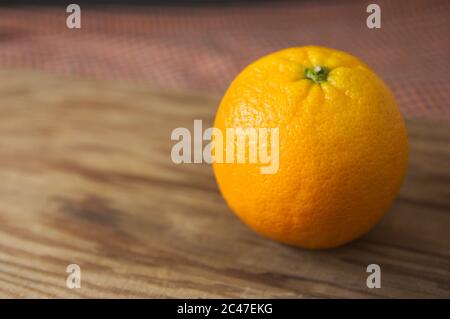 Closeup of a ripe orange on a wooden table with dark background and with space for texts (copy space) Stock Photo
