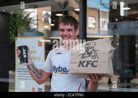 Eastleigh Hampshire, UK. June 24th 2020, Young man with tattoos on arms smiling and happy holding paper Kentucky fried chicken and soft drink, Eastleigh, Hampshire, UK Credit: Dawn Fletcher-Park/Alamy Live News Stock Photo