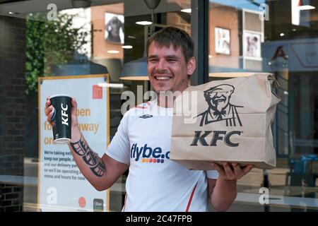 Eastleigh Hampshire, UK. June 24th 2020, Young man with tattoos on arms smiling and happy holding paper Kentucky fried chicken and soft drink, Eastleigh, Hampshire, UK Credit: Dawn Fletcher-Park/Alamy Live News Stock Photo
