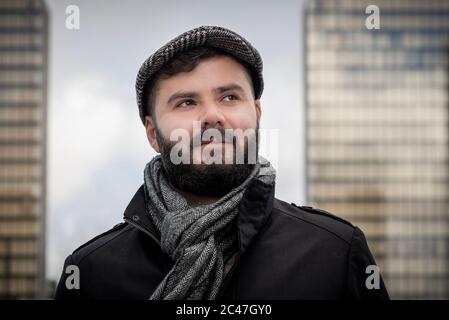 Young handsome french bearded man, taken outside with buildings behind with natural light in Paris, France Stock Photo