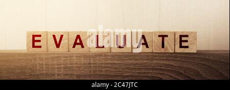 Evaluate word on natural wooden cubes on wooden table. Business and education concept Stock Photo