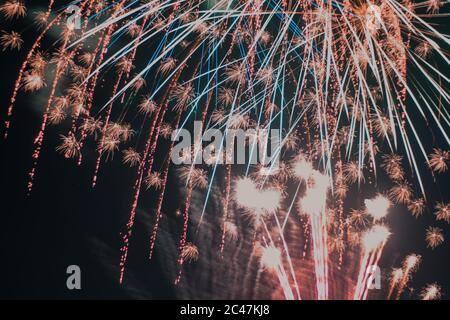 Low angle shot of fireworks of various colors exploding against a black background Stock Photo