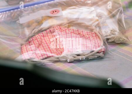 Deluxe fabric mask in plastic bag ready to ship sitting on table blown out background and foreground Stock Photo