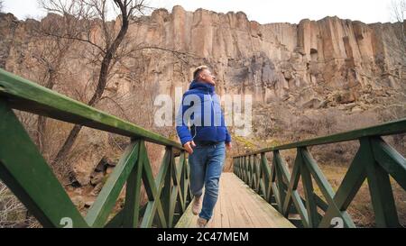 Happy tourist runs on a bridge over a river in the Ihlara Valley in Cappadocia, Turkey. Stock Photo