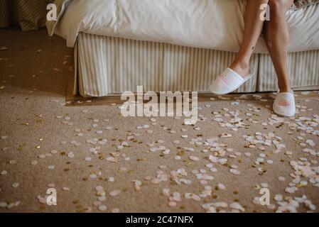 Attractive woman sitting on the bed wearing white slippers Stock Photo