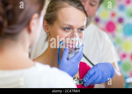 Pretty, young woman being taken care of by medics in a hospital - udergoing a check, getting oxygen Stock Photo