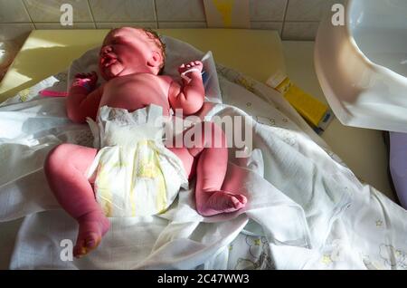 New born baby - girl with remainder of umbilical cord after successful childbirth. Real birthing and new born baby in a hospital. A healthy female Stock Photo